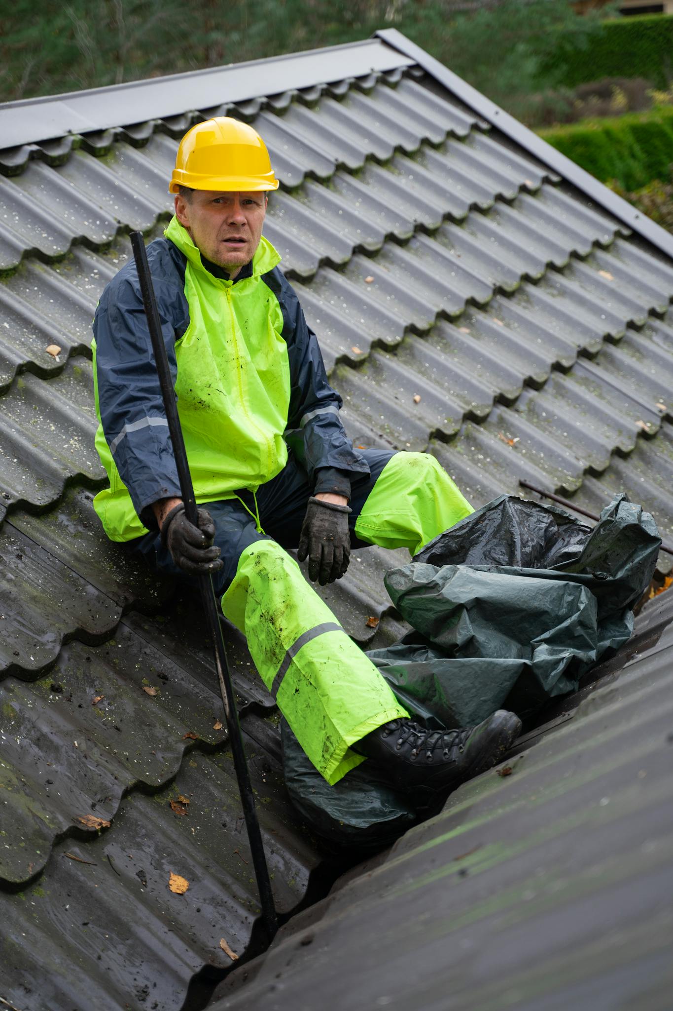 A construction worker in safety gear performing roof maintenance outdoors.