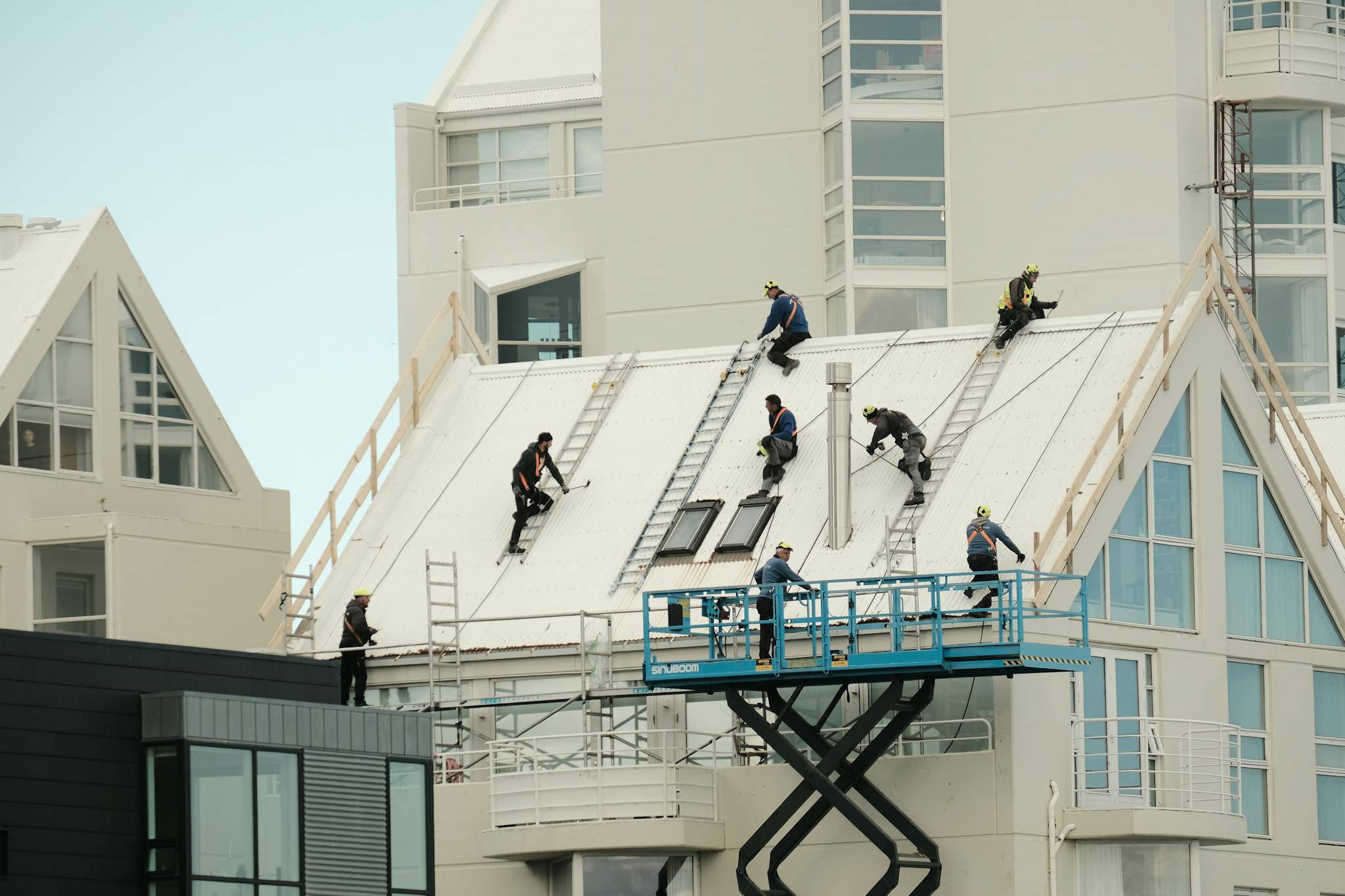 Construction workers repairing a modern roof in Reykjavík, highlighting teamwork and safety.