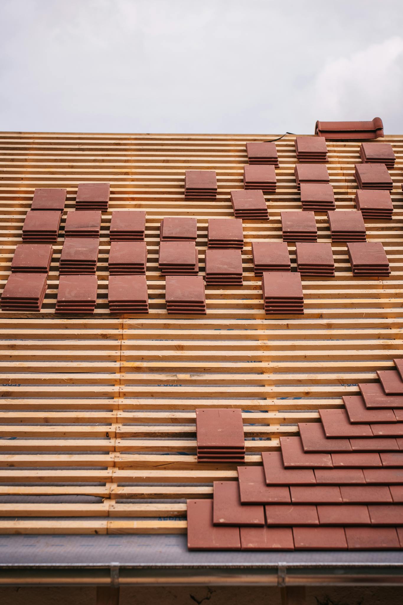 View of a roof under construction with red tiles and wooden lattice framework, showcasing modern architecture techniques.
